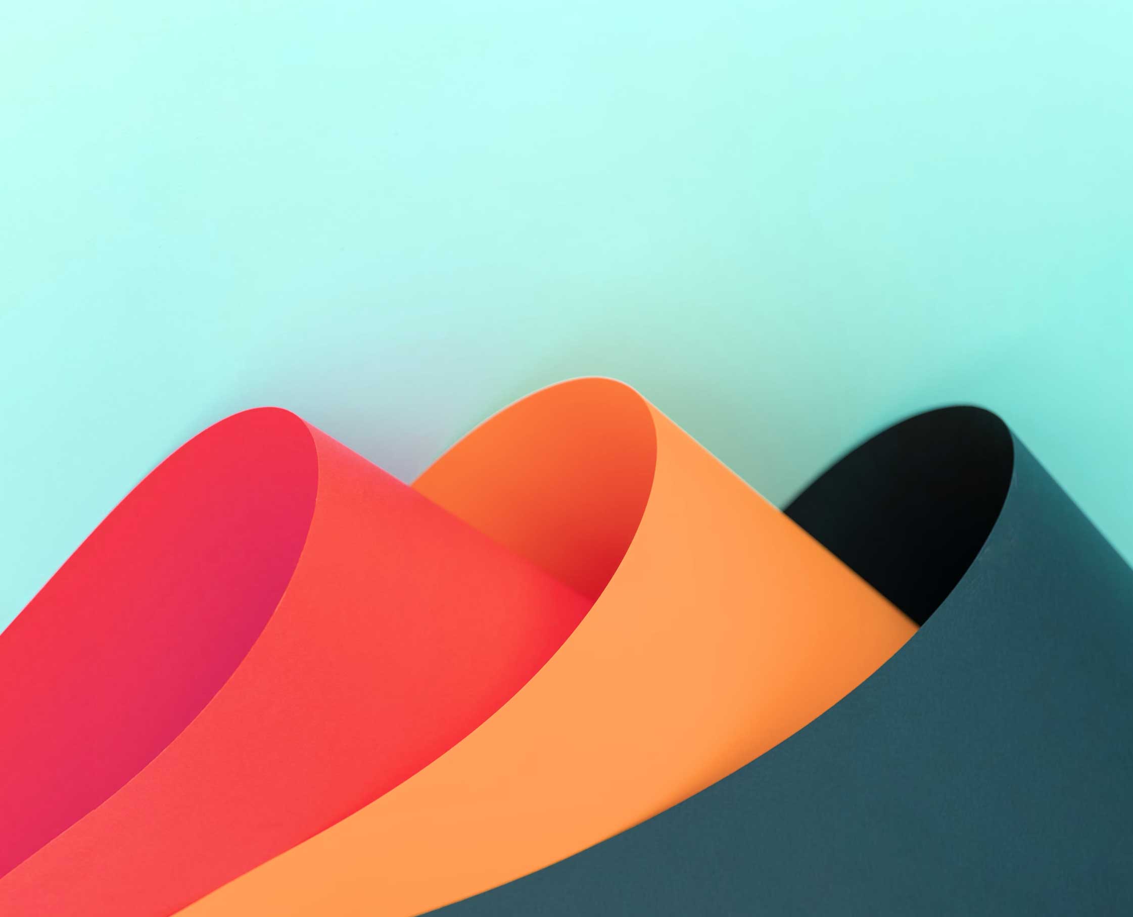 Three brightly colored papers overlapping to make wave shapes.